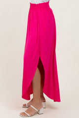 woman wearing a hot pink maxi skirt with a high low hem and side slit, paired with white block-heeled sandals