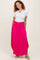 woman wearing a gray short sleeve henley top and a bright pink maxi skirt, standing and smiling