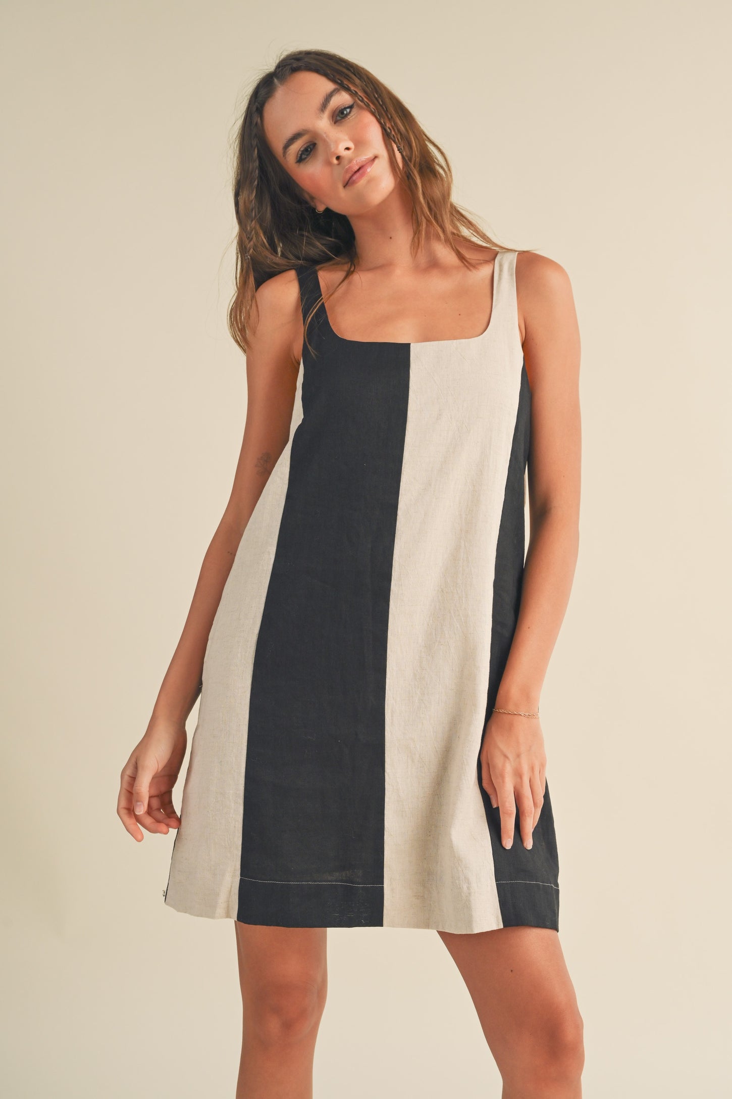woman wearing a black and cream striped sleeveless dress with a square neckline
