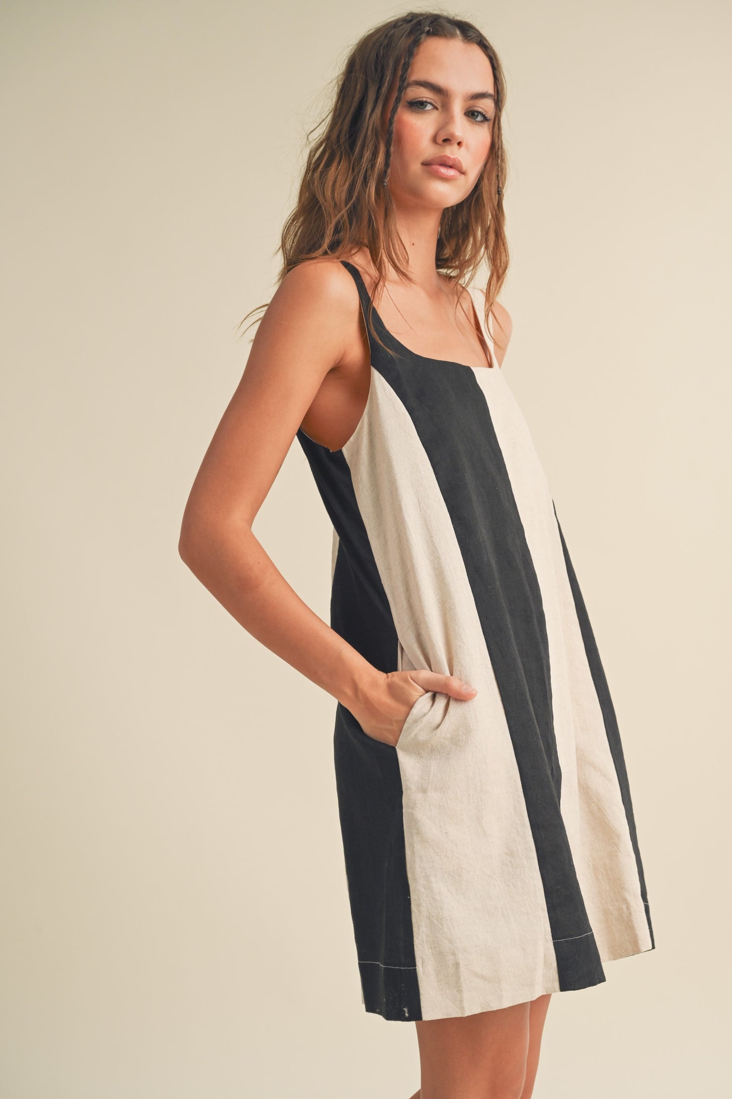 woman wearing a black and cream striped sleeveless dress with pockets