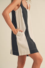 woman wearing a sleeveless black and white striped shift dress with side pockets