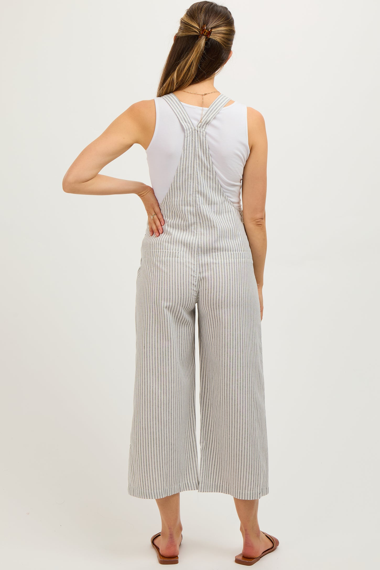 woman wearing a white striped maternity jumpsuit with wide legs and a fitted bodice, showing her back
