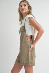woman wearing a white ribbed short sleeve top and olive green short overalls with pockets