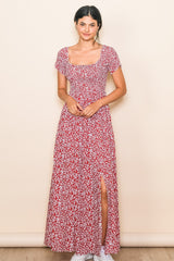 woman wearing a red floral maxi dress with short sleeves and a thigh-high slit, standing against a neutral background