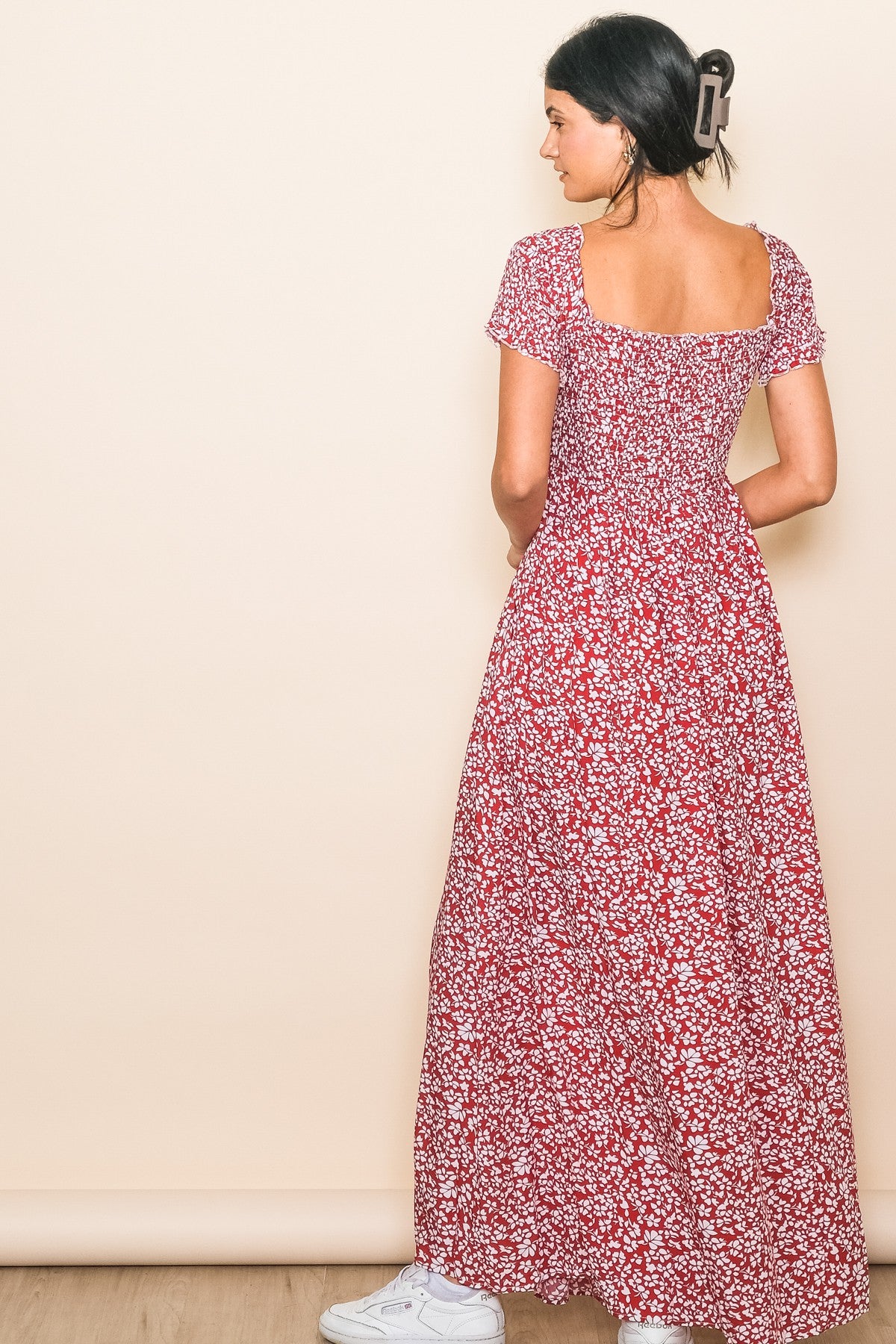 woman wearing a red floral maxi dress with short sleeves and a square neckline, showing the back view