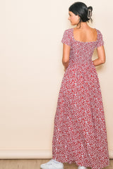 woman wearing a red floral maxi dress with short sleeves and a square neckline, showing the back view