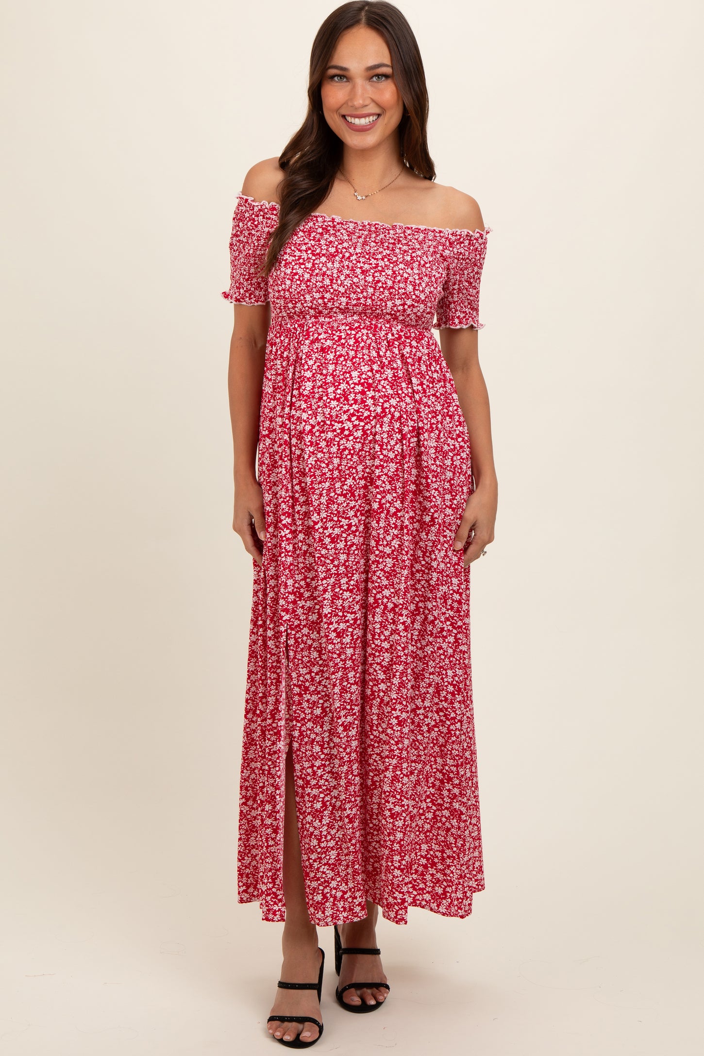 woman wearing a pink floral off-the-shoulder maternity maxi dress with a thigh-high slit and visible baby bump