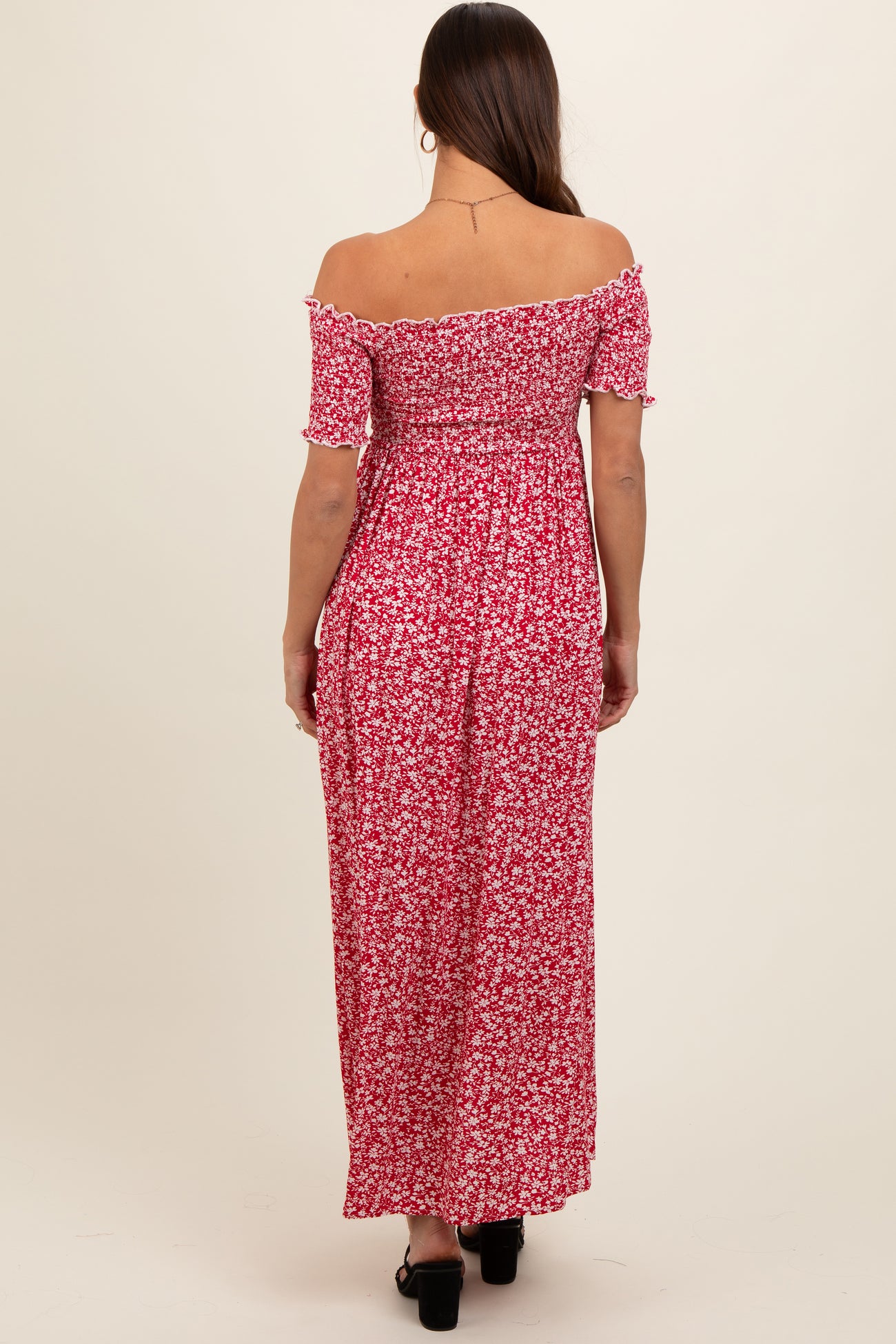 woman wearing a red floral off-the-shoulder maternity maxi dress, viewed from the back