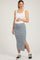 woman wearing a white tank top and a light blue maternity midi skirt with side slits, showing her baby bump