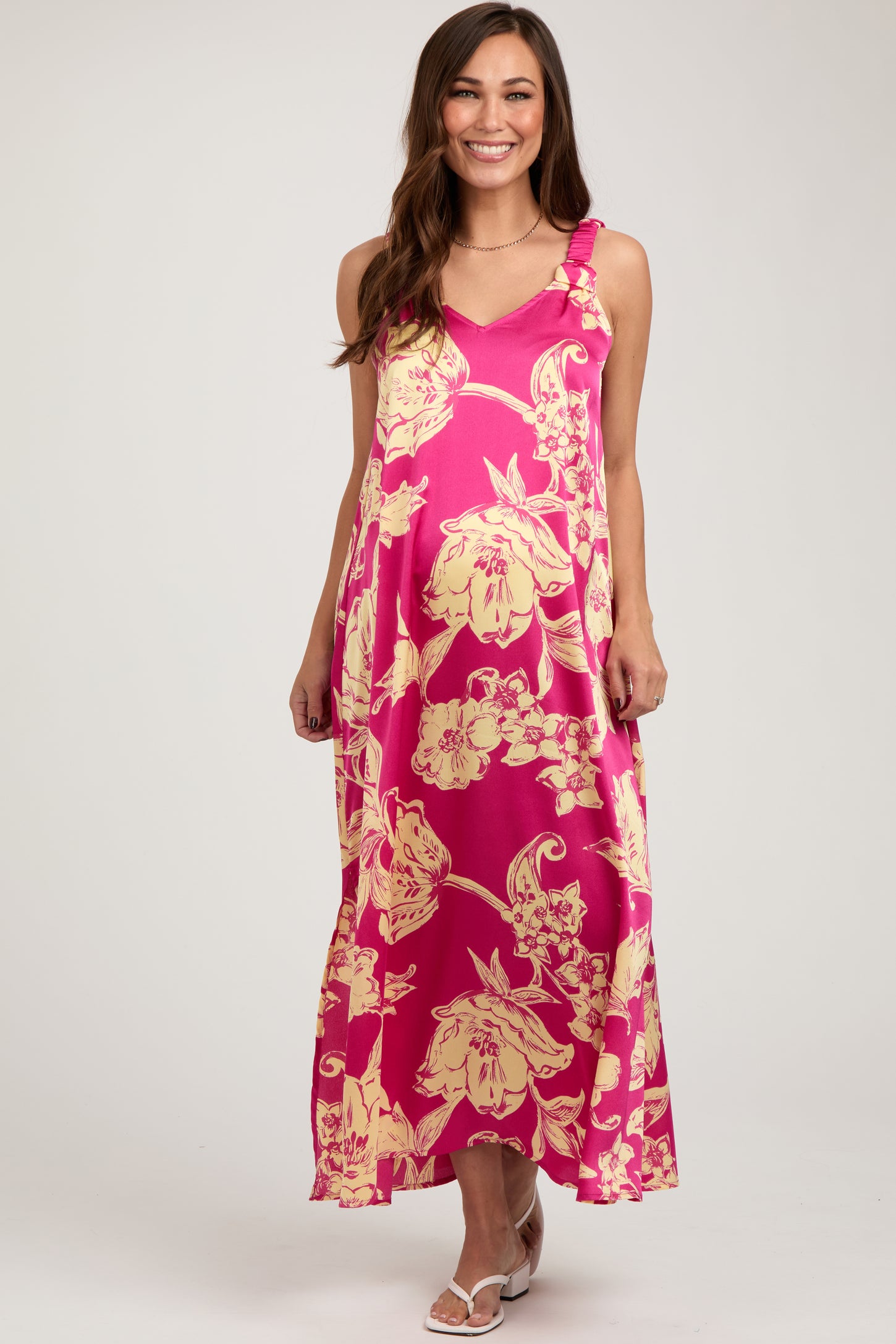 woman wearing a pink floral maternity maxi dress with adjustable straps and a flowing silhouette, showing her baby bump