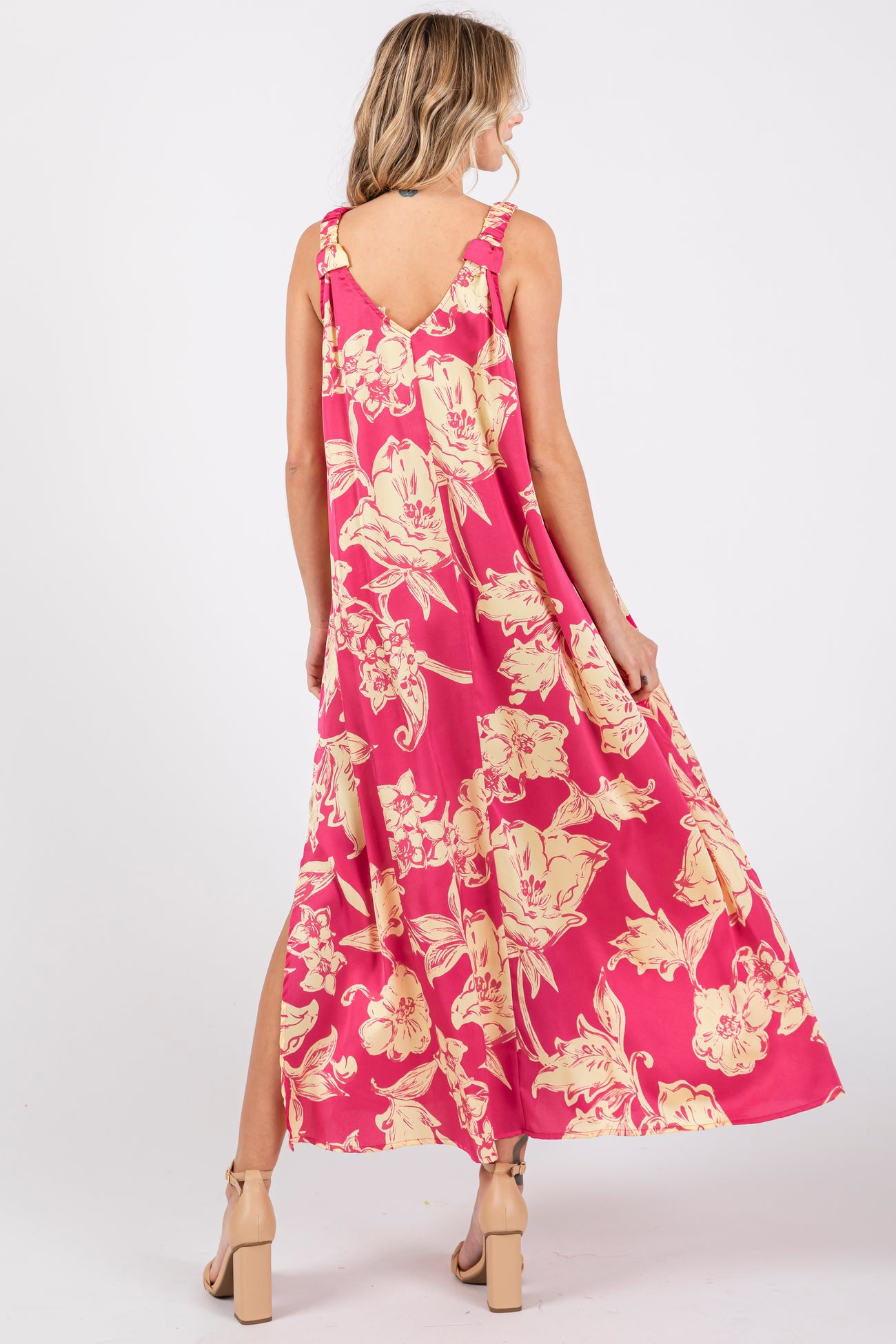 woman wearing a pink floral maxi dress with a low back and side slits, shown from the back