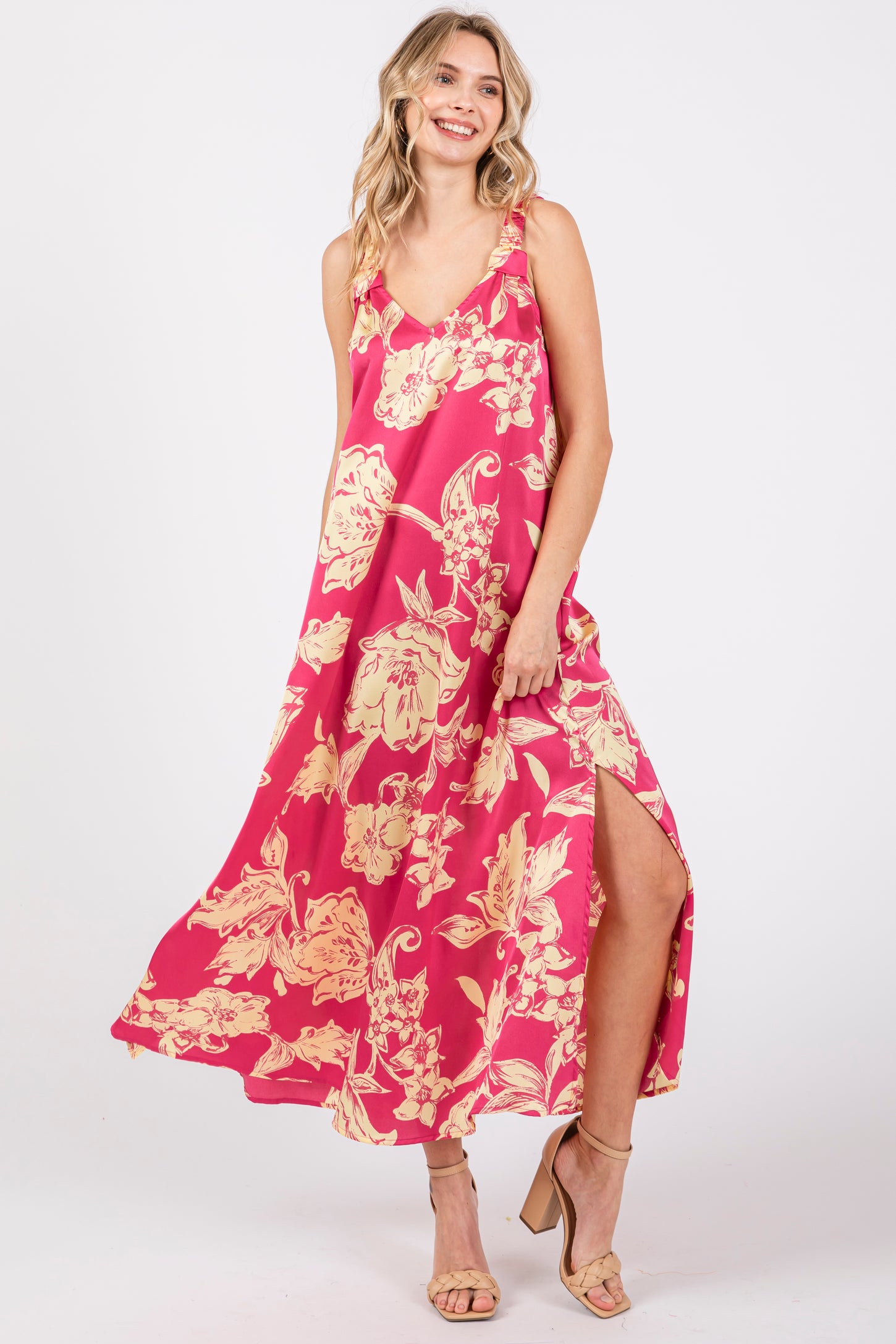 woman wearing a pink floral maxi dress with a side slit and adjustable straps