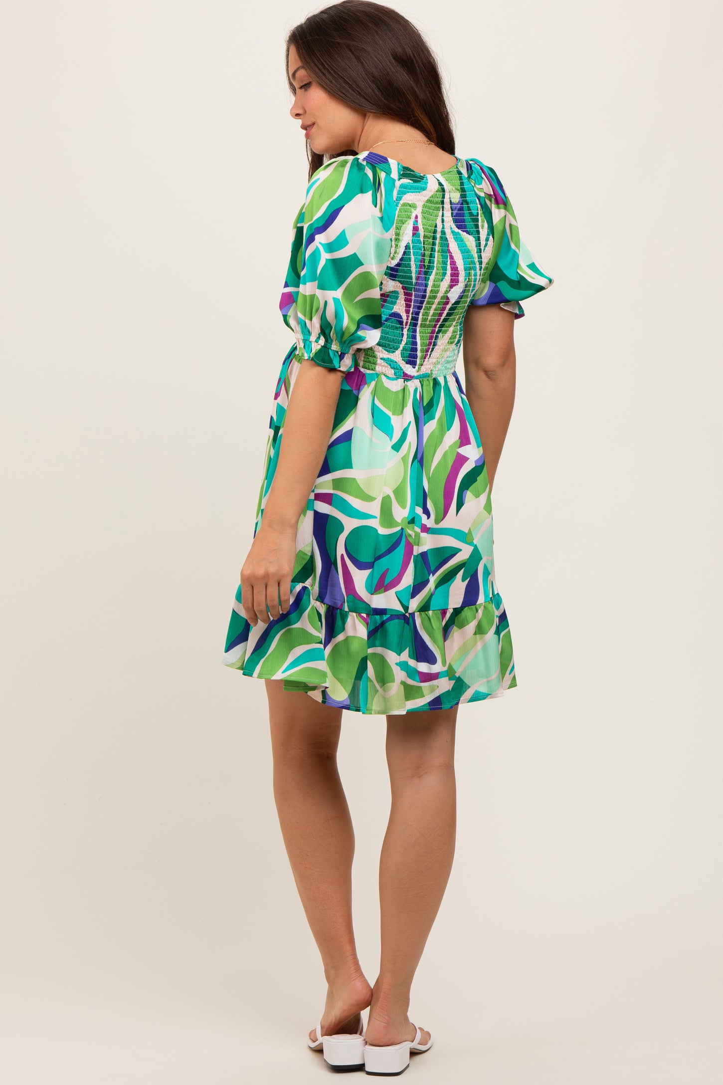 woman wearing a colorful maternity dress with puff sleeves and a tiered skirt, showcasing a relaxed fit from the back