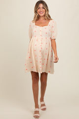 woman wearing a light pink maternity dress with floral prints and puff sleeves, showing a baby bump