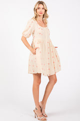 woman wearing a cream short puff sleeve dress with red floral embroidery and pockets