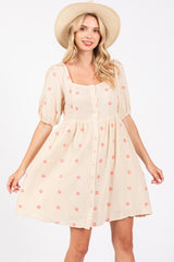 woman wearing a beige puff sleeve floral print dress with a square neckline and buttons down the front