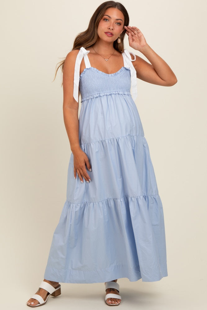 woman wearing a light blue maternity maxi dress with smocked bodice and white tie straps, showcasing a baby bump