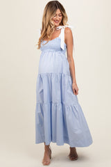 woman wearing a light blue maternity maxi dress with smocked bodice and tie straps, showcasing her baby bump