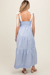 woman wearing a light blue maternity maxi dress with tie straps and a tiered skirt, showing a flowing back design