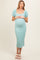 woman wearing a mint green puff sleeve maternity dress with textured detail, showcasing her baby bump