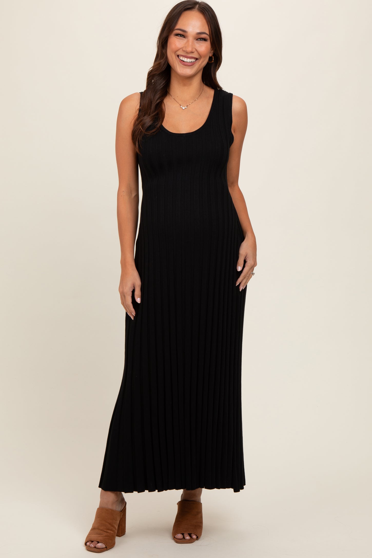 woman wearing a black ribbed maxi maternity dress with a fitted silhouette and sleeveless design