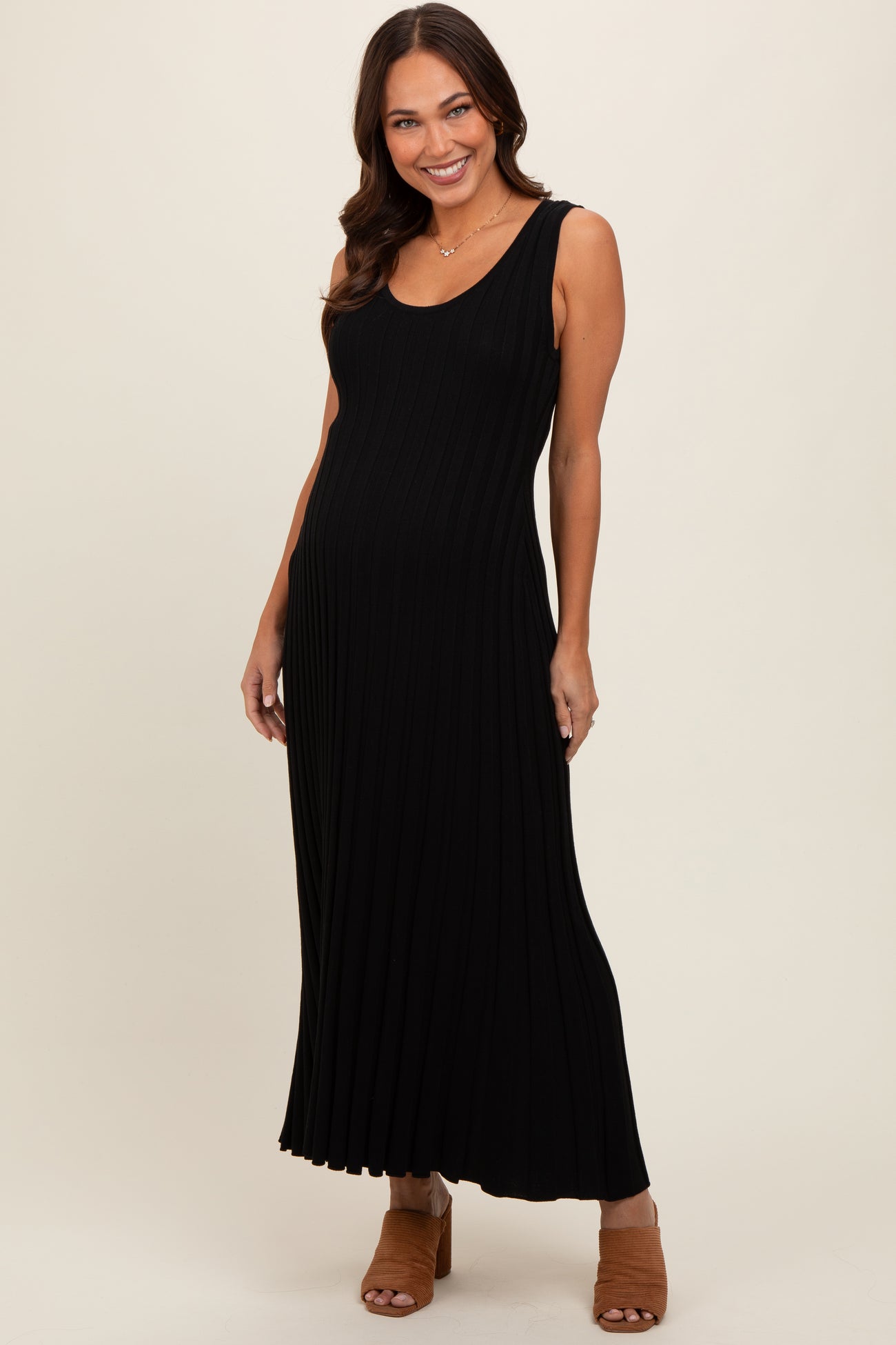 woman wearing a black ribbed maternity maxi dress with a scoop neckline and a fitted silhouette, showing her baby bump