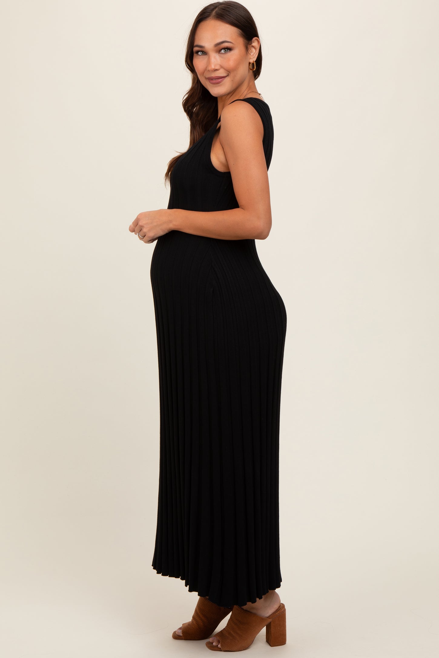 woman wearing a black ribbed maternity maxi dress, showing her baby bump and smiling to the side