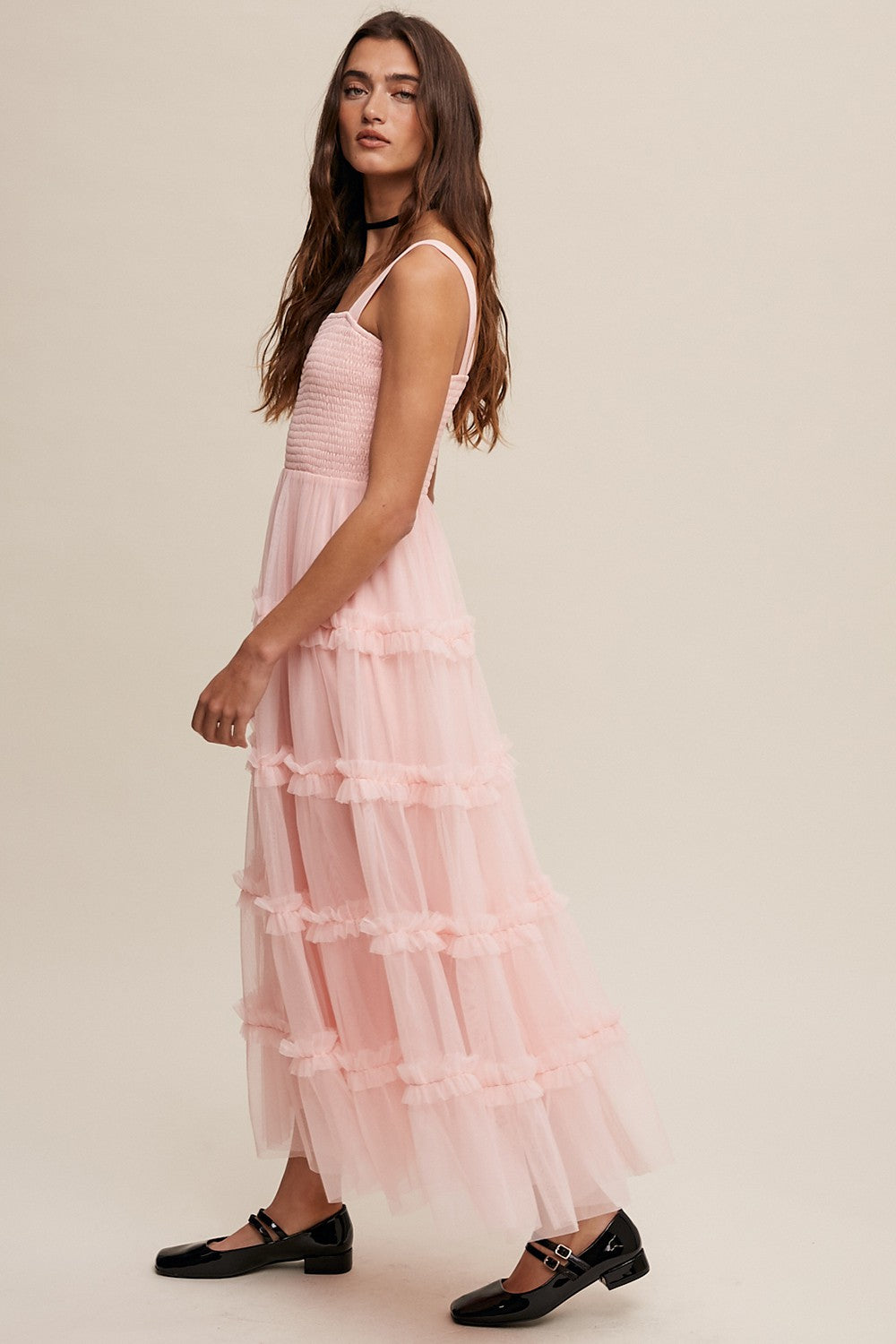 woman wearing a light pink tiered maxi dress with ruffled details and spaghetti straps