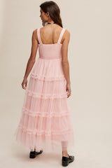 woman wearing a light pink tiered tulle maxi dress with a smocked bodice and wide straps, viewed from the back
