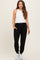 woman wearing black maternity joggers and a white sleeveless top, with pockets and elastic cuffs at the ankles