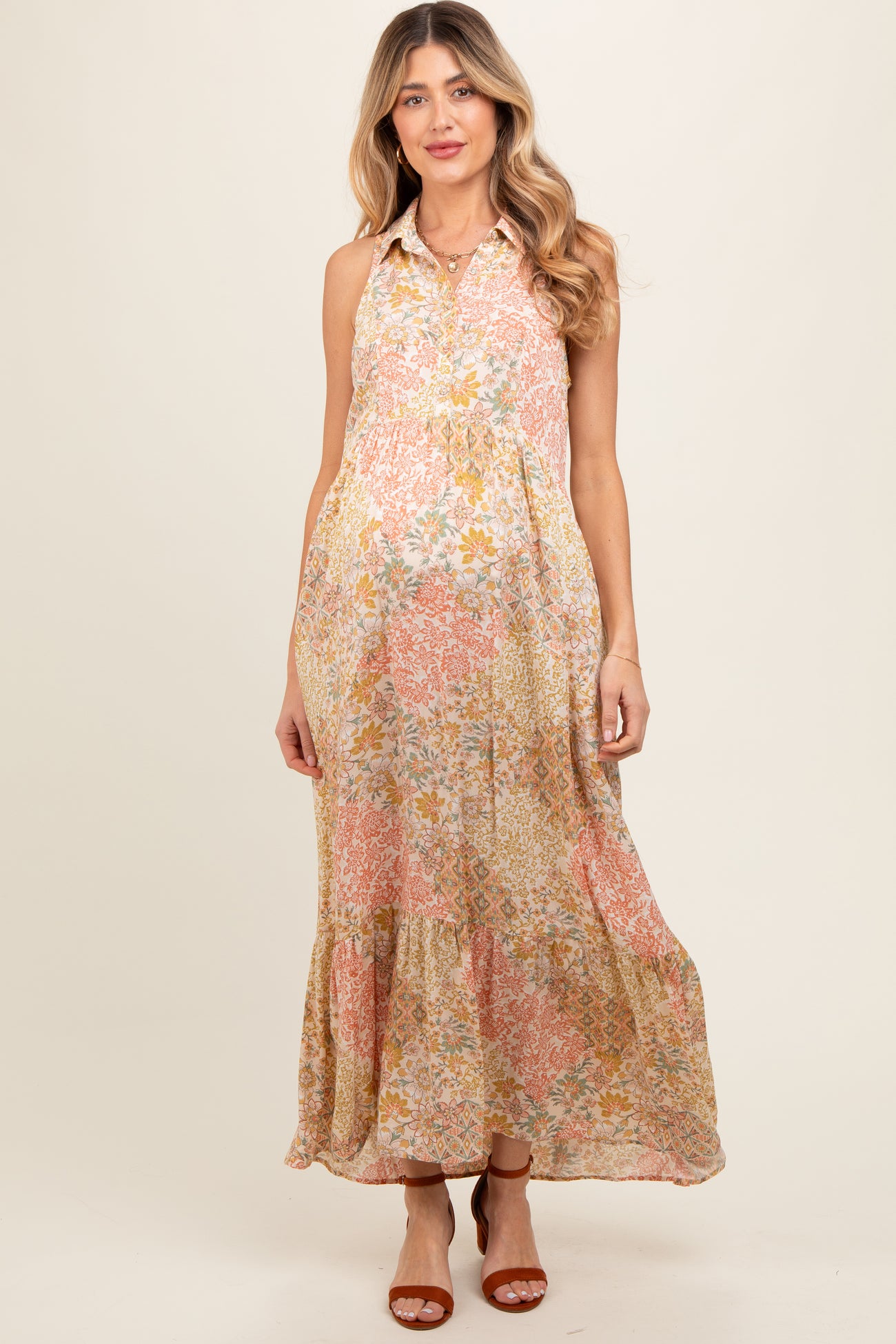 woman wearing a floral print sleeveless maternity maxi dress with a tiered skirt and a button-down collar