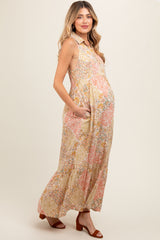 woman wearing a floral print sleeveless maternity maxi dress with pockets and a visible baby bump