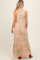woman wearing a sleeveless floral patterned maternity maxi dress with a tiered skirt and a cowl neckline