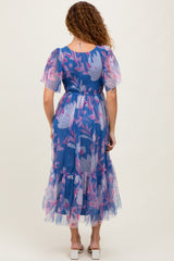 woman wearing a sheer blue floral maxi dress with puff sleeves and a ruffled hem, seen from the back