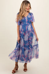 woman wearing a blue floral maternity dress with short flutter sleeves and a tiered skirt, showcasing her baby bump