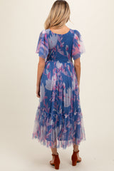 woman wearing a blue floral maternity dress with flutter sleeves and a layered skirt, showing a baby bump from the back