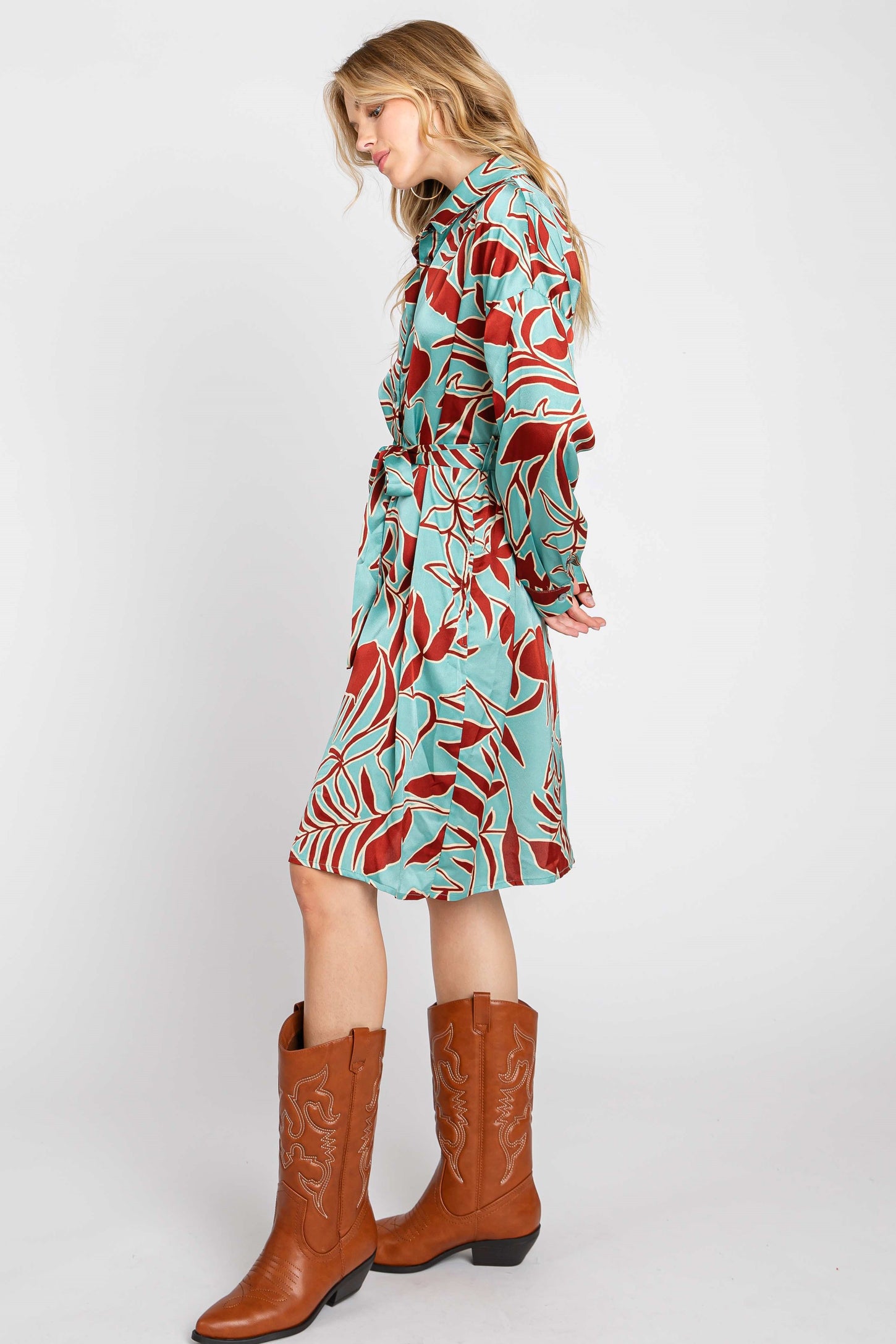 woman wearing a turquoise and red floral print dress with a belt and brown cowboy boots