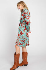 woman wearing a turquoise and red floral print dress with a belt and brown cowboy boots