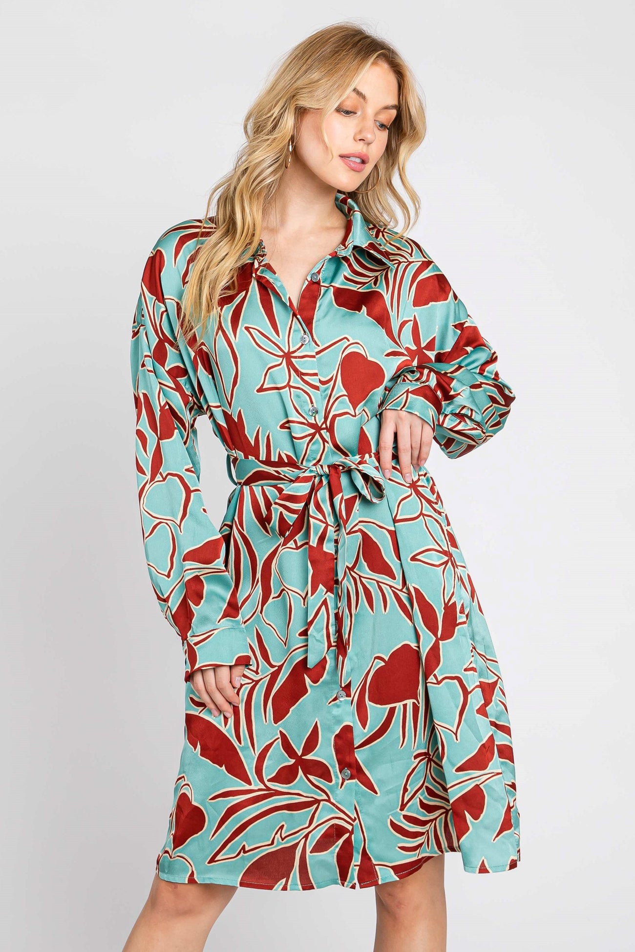 woman wearing a turquoise shirt dress with a red floral print and a belt around the waist