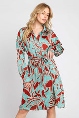 woman wearing a turquoise shirt dress with a red floral print and a belt around the waist