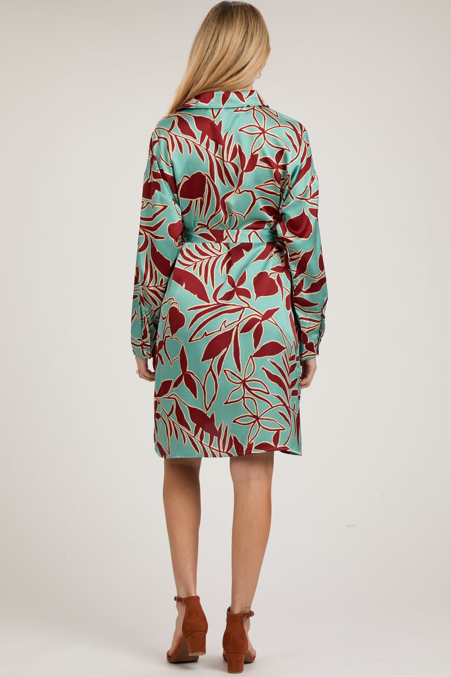 woman wearing a mint green floral maternity dress with long sleeves and a belt, showing a baby bump from the back