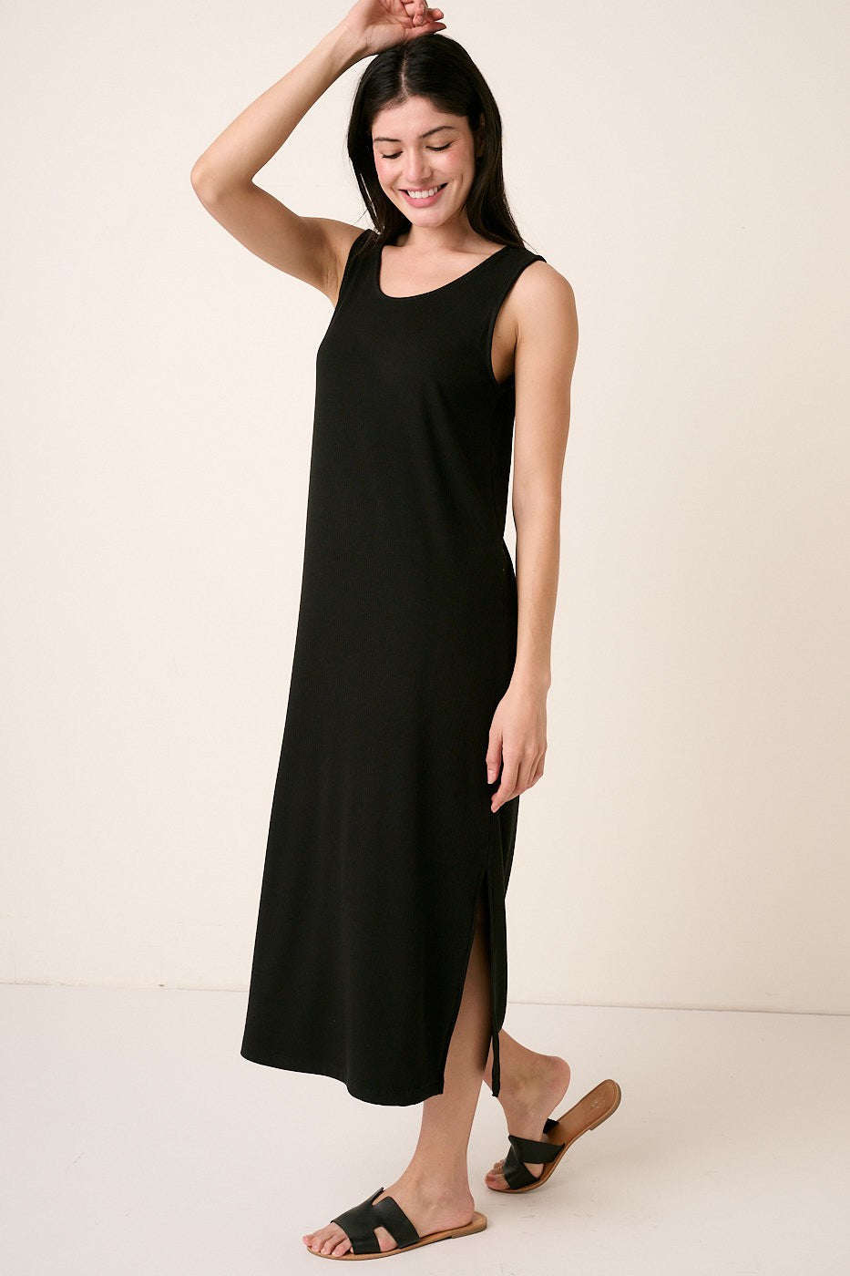 woman wearing a black sleeveless maxi dress with side slits and a relaxed fit, standing gracefully