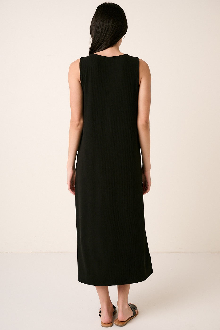 woman wearing a black sleeveless maxi dress, shown from the back