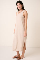 woman wearing a beige sleeveless maxi dress with side slits and a relaxed fit