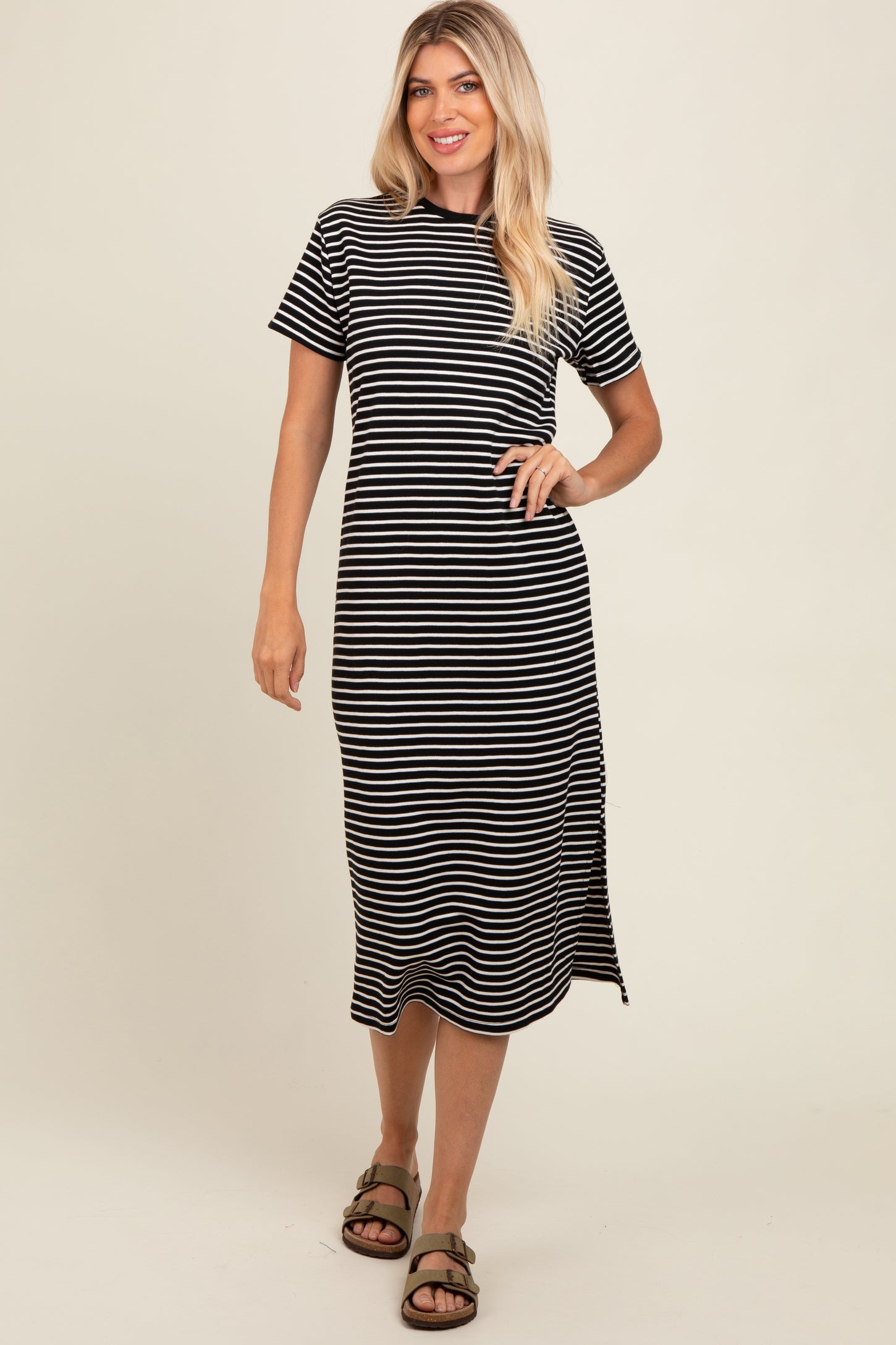woman wearing a black and white striped short sleeve midi dress with a side slit