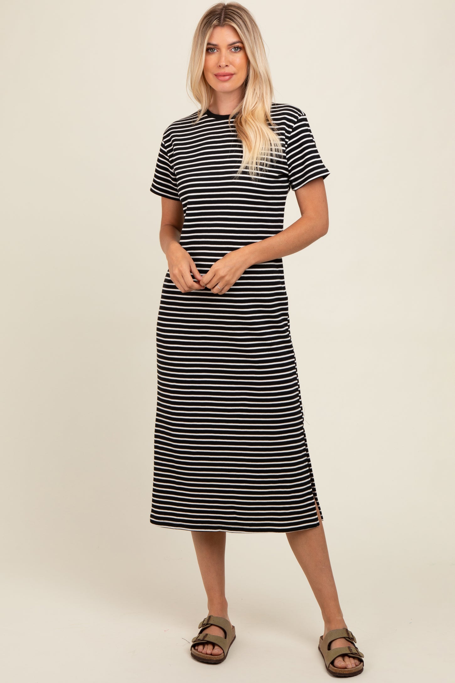 woman wearing a black and white striped short sleeve midi dress with side slits and a relaxed fit