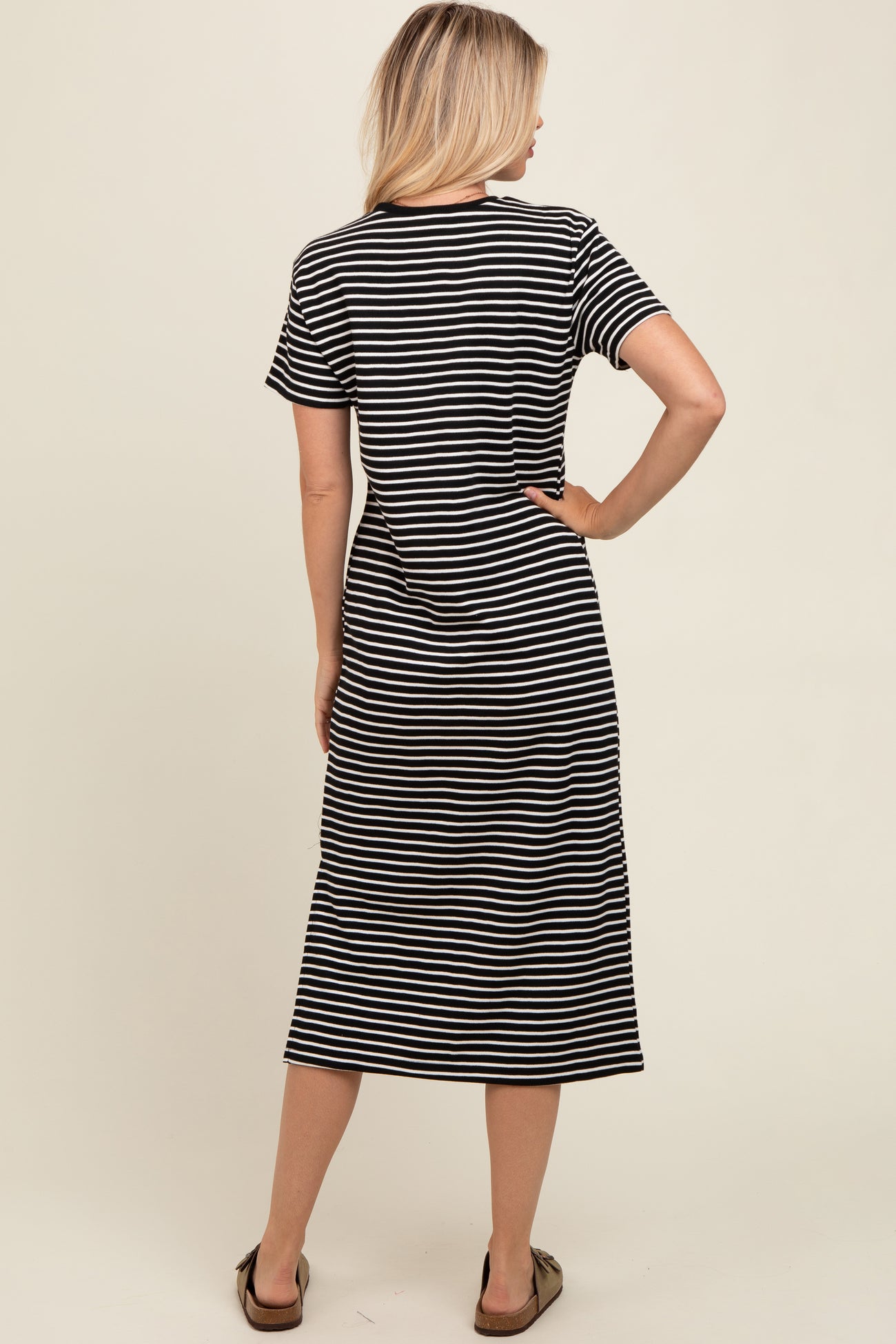woman wearing a black and white striped short sleeve maxi dress, standing with her back to the camera