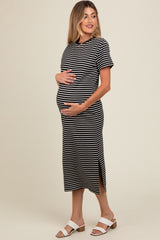 woman wearing a black and white striped maternity dress with a relaxed fit and side slits, cradling her baby bump