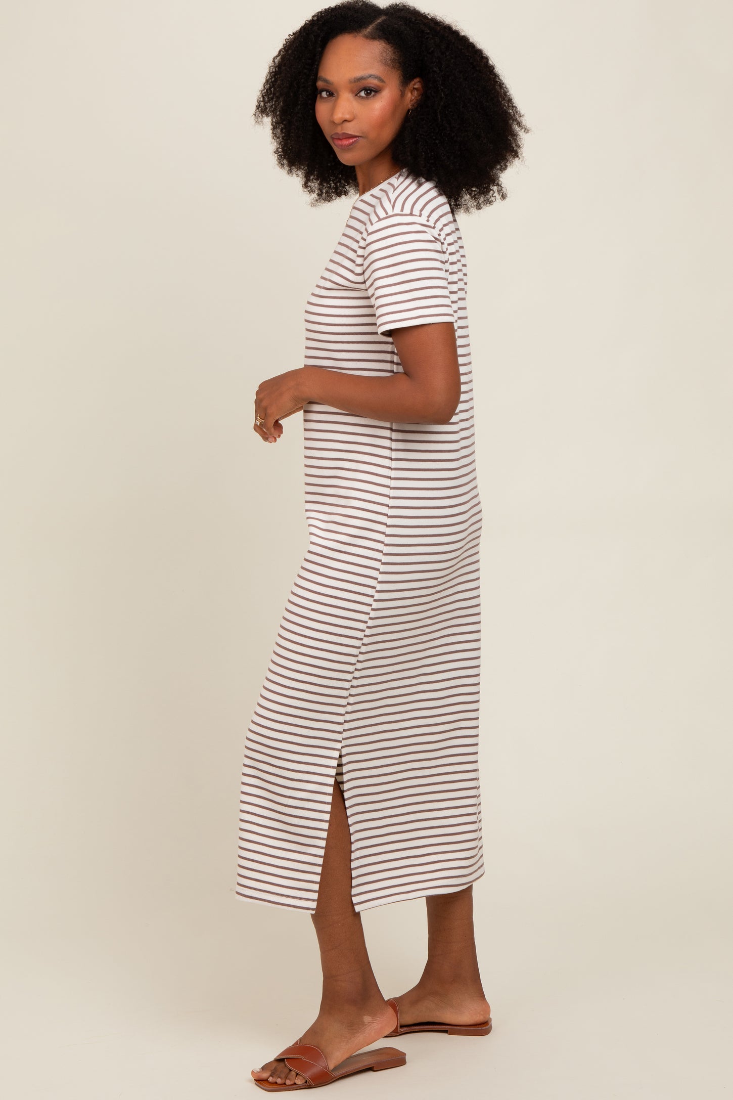 woman wearing a beige and white striped short sleeve maxi dress with side slits and brown sandals
