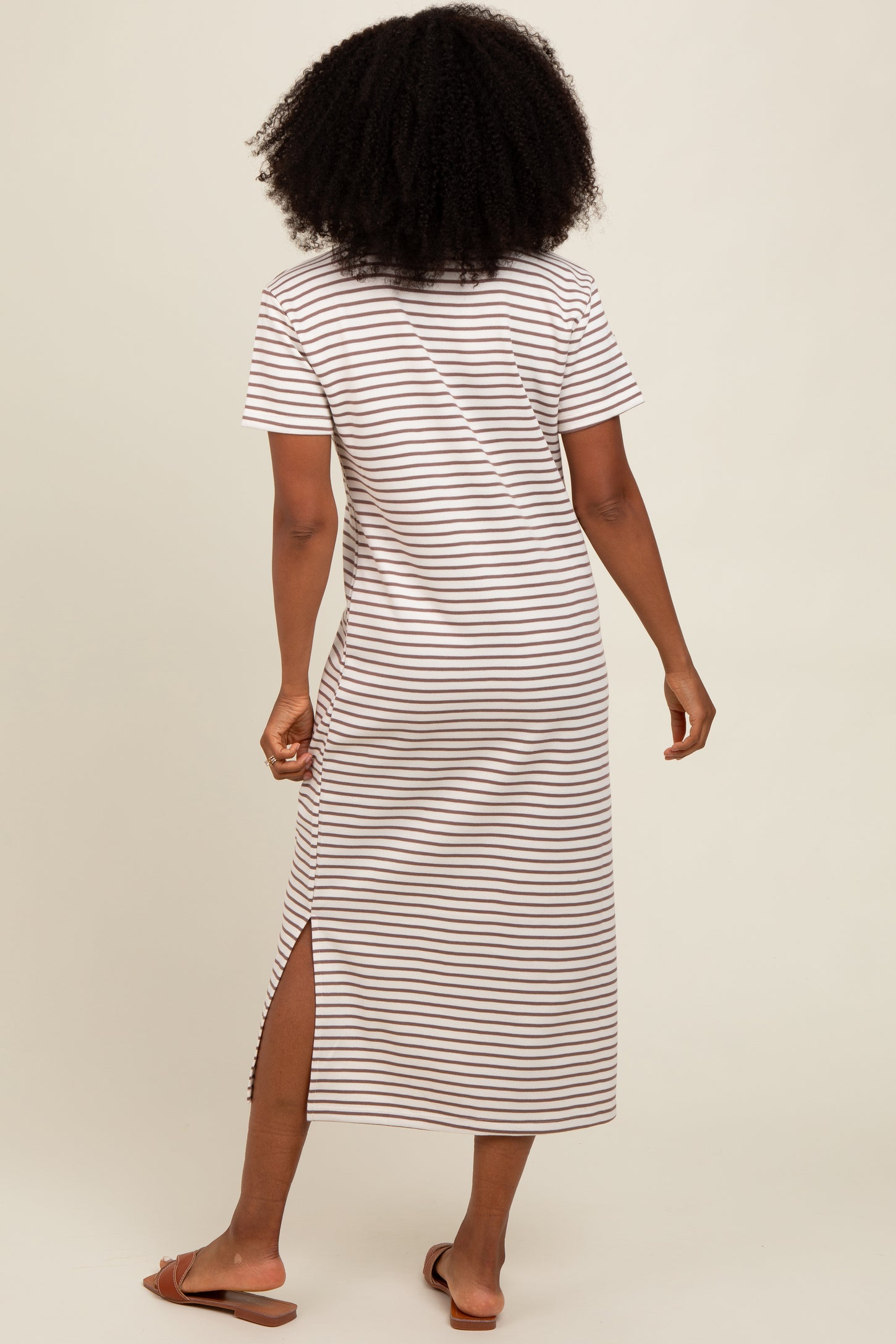 woman wearing a brown and white striped short sleeve maxi dress with side slits, seen from the back